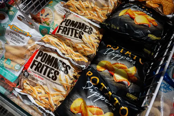 Lviv, Ukrayna - 25 Mart 2025: Bir süpermarkette sergilenen çeşitli donmuş patates ürünleri ve paketlenmiş hamur tatlısı.