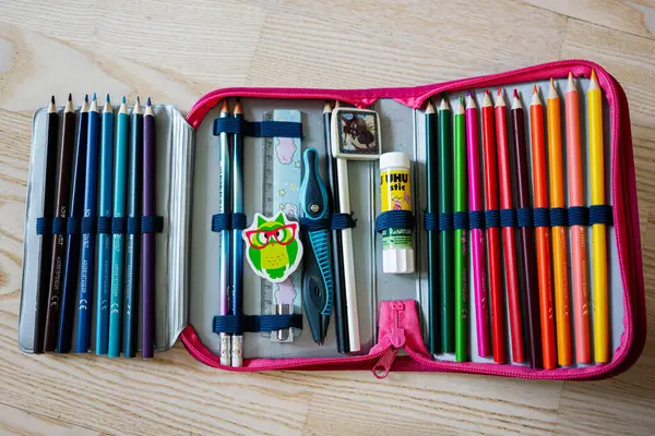 Lviv, Ukrayna - 25 Mart 2025: Renkli kalem kutusu kalemler, keskinleştirici, yapıştırıcı ve okulun temel gereksinimleri düzgünce düzenlenmiş.