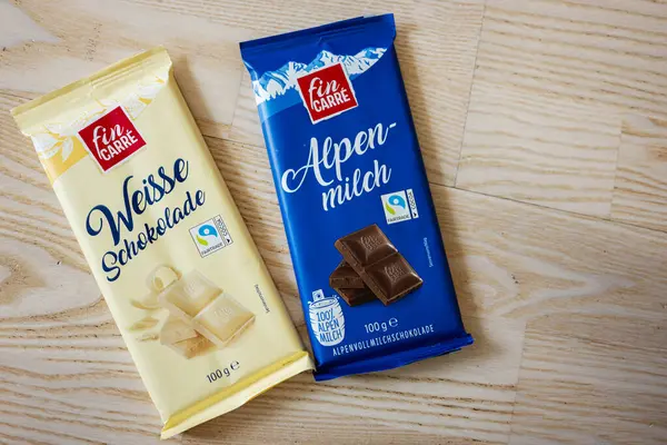 Lviv, Ukrayna - 25 Mart 2025: İki Fin Carre çikolatası, beyaz ve süt, ahşap arka planda.