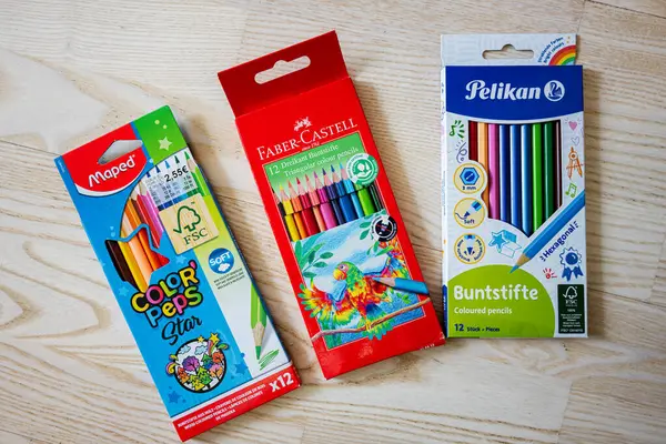 Lviv, Ukrayna - 25 Mart 2025: Ahşap bir masa üzerinde Haritalanmış, Faber-Castell ve Pelikan marka renkli ambalajlar