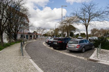 Fatima, Portekiz - 24 Mart 2025: Fatima, Portekiz 'de açık bir gökyüzü altında park halindeki arabaları gösteren sokak manzarası