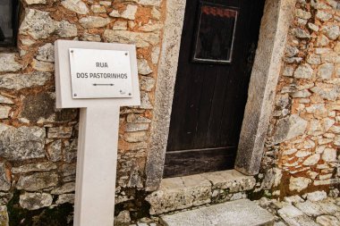 Fatima, Portekiz - 24 Mart 2025: Portekiz Fatima, Portekiz 'de ahşap kapılı ve yön işareti Rua Dos Pastorinhos olan eski taş duvar