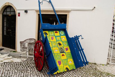 Fatima, Portekiz - 24 Mart 2025: Portekiz 'deki kaldırımlı bir sokakta renkli detaylarla dolu sanatsal ahşap el arabası