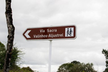 Fatima, Portekiz - 24 Mart 2025: Portekiz 'in Fatima şehrinde bulutlu bir gökyüzü altında, Via Sacra cazibesini gösteren yön işareti.