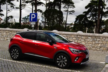 Fatima, Portekiz - 24 Mart 2025: Portekiz, Fatima 'da park yeri, kırmızı bir Renault CAPTUR arabası ve doğal manzara. 