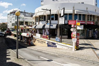 Fatima, Portekiz - 26 Mart 2025: Portekiz 'in Fatima şehrinde alışveriş ve tabelalar güneşli bir sokak köşesi hizasında.