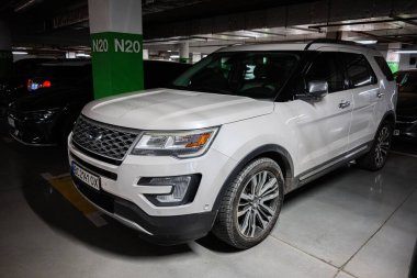 Lviv, Ukrayna - 31 Mart 2025: Geceleri kapalı bir yeraltı garajına park edilmiş beyaz bir Ford Explorer Platinum SUV 'ye yakın plan.
