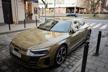 Lviv, Ukrayna - 31 Mart 2025 Ukrayna 'nın başkenti Lviv' de bir kaldırım taşı caddesinde altın rengi bir Audi E-tron GT araba