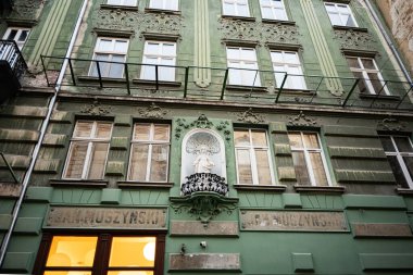 Lviv, Ukrayna - 31 Mart 2025: Yeşil sanatsal Jan Muszynski cephesi Lviv, Ukrayna 'da karmaşık bir tasarım ve dini bir heykel sergiliyor