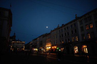 Lviv, Ukrayna - 31 Mart 2025: Aydınlatılmış binalar, gezinen insanlar ve Ukrayna 'nın tarihi mimarisi. 