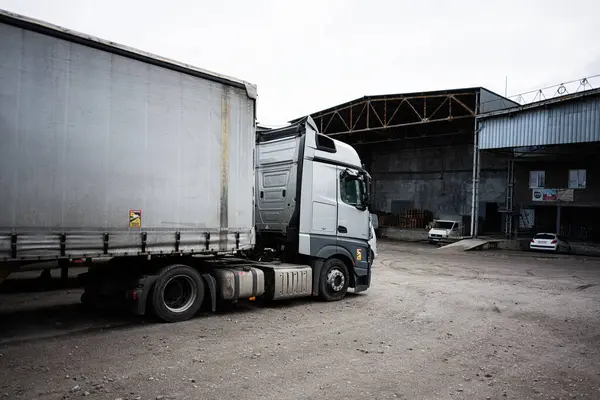 Lviv, Ukrayna - 31 Mart 2025: Geniş bir sanayi deposu ve arkaplan binalarının yakınındaki park halindeki bir kamyonun görüntüsü