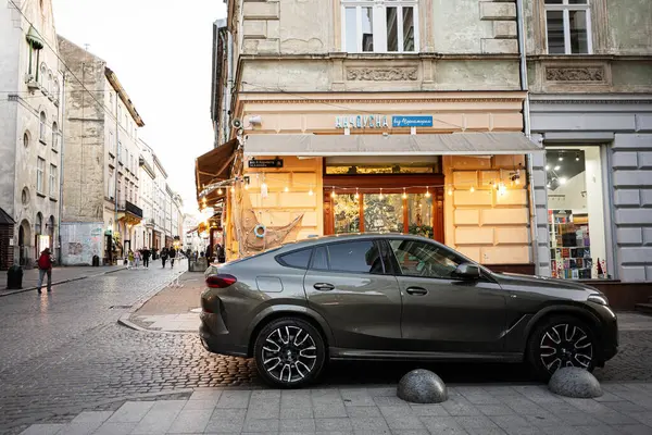 Lviv, Ukrayna - 31 Mart 2025: Ukrayna 'nın başkenti Lviv' de bulunan tarihi binalar ve yayalar vasıtasıyla BMW X6 aracı. 