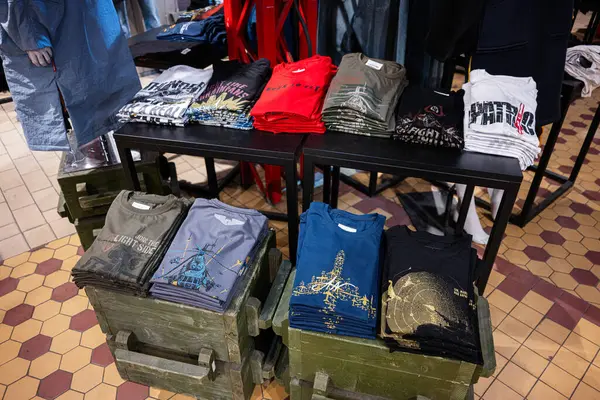 Lviv, Ukrayna - 31 Mart 2025: Düzgünce katlanmış grafik tişörtlerinin koleksiyonu bir mağazada sergileniyor.