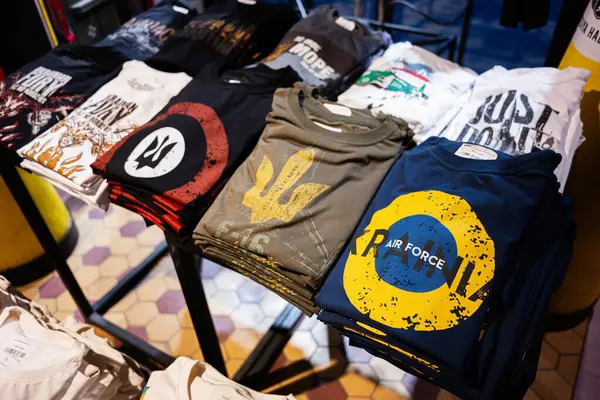 Lviv, Ukrayna - 31 Mart 2025: Bir perakende mağazasında düzgünce sergilenen çeşitli renkli grafik tişörtleri