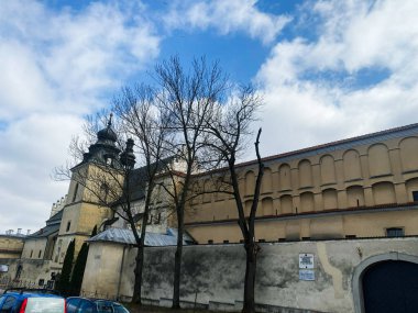 Krakow, Polonya - 16 Mart 2025: Krakow, Polonya 'da ağaçlar, bulutlar ve parlak bir atmosferle tarihi mimari.