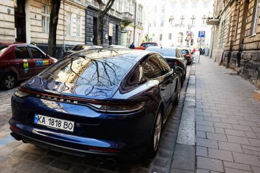 Lviv, Ukrayna - Nisan 01, 2025: Lüks Porsche Panamera 4 otomobil Lviv, Ukrayna 'da klasik mimariye sahip şehir caddesinde