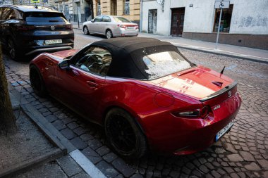 Lviv, Ukrayna - 01 Nisan 2025: Üstü açık kırmızı Mazda MX-5 spor araba Lviv 'de bir kaldırım taşı caddesinde park edilmiş..
