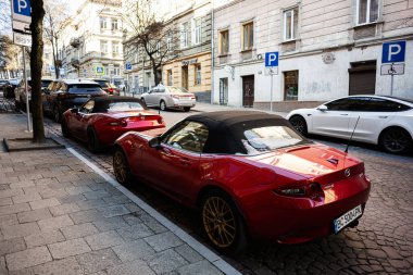 Lviv, Ukrayna - 1 Nisan 2025: İki kırmızı spor araba Mazda MX-5 Lviv 'de manzaralı tarihi bir cadde boyunca park halinde görüldü.