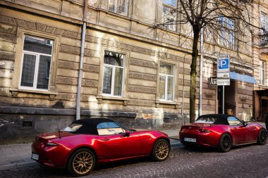 Lviv, Ukrayna - 01 Nisan 2025: İki üstü açık Mazda MX-5 Lviv 'deki tarihi bir binanın yakınındaki kaldırım taşı bir sokakta