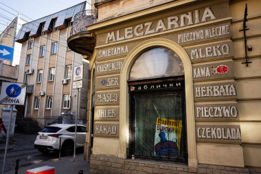 Lviv, Ukrayna - Nisan 01, 2025: Lviv 'deki tarihi mağaza Mleczarnia adlı Polonya metnini sergiliyor ve modern şehir binalarıyla çevrili