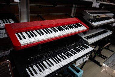 Lviv, Ukrayna - 01 Nisan 2025: Kırmızı dijital Casio klavyesi benzer enstrümanlarla çevrili bir müzik mağazasında belirgin bir şekilde sergilendi.