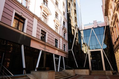 Lviv, Ukrayna - Nisan 01, 2025: Lviv 'in şehir merkezindeki klasik stil mimariye karşı çağdaş cam yapı