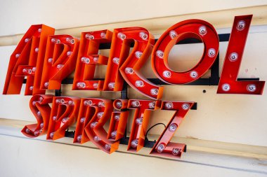 Lviv, Ukrayna - Nisan 06, 2025: Duvarda kırmızı ve sarı renkler bulunan parlak ışıklı Aperol Spritz işareti.