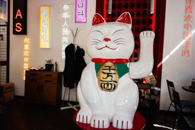 Lviv, Ukrayna - Nisan 06, 2025: Neon ışıklı Çin tabelasının yer aldığı bir restoranın içine yerleştirilmiş dev bir maneki-neko