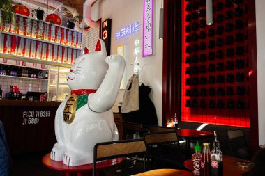 Lviv, Ukrayna - Nisan 06, 2025: Büyük bir Maneki Neko heykeli ve şık bir dekorun sergilendiği modern bir yemek alanı