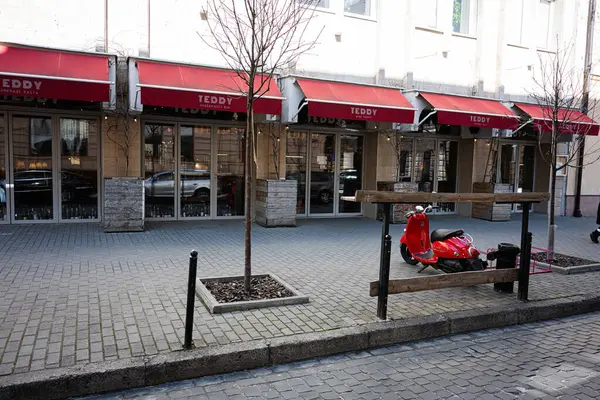 Lviv, Ukrayna - Nisan 06, 2025: Kırmızı tenteli bir kafe ve park halindeki kırmızı scooterin Lviv, Ukrayna.