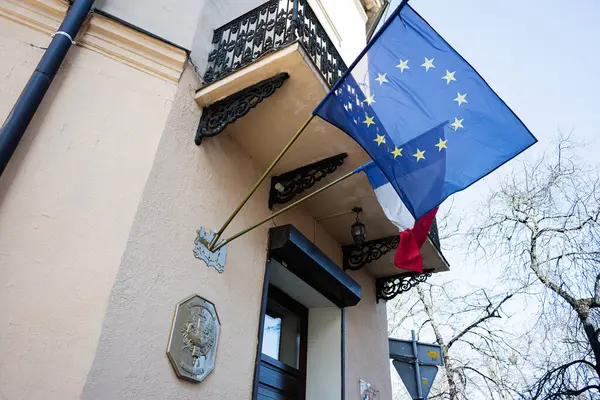 Lviv, Ukrayna - Nisan 06, 2025: Avrupa ve Fransız bayrakları parlak bir gökyüzüne karşı dekoratif balkonları olan bir binayı süslüyor.