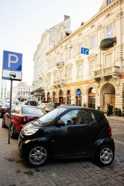 Lviv, Ukrayna - Nisan 06, 2025: Ukrayna 'nın başkenti Lviv' de güneşli bir günde, tarihi binaların önündeki Black Smart Fortwo kompakt araba.