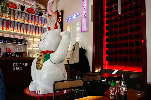 Lviv, Ukrayna - Nisan 06, 2025: Büyük bir Maneki Neko heykeli ve şık bir dekorun sergilendiği modern bir yemek alanı