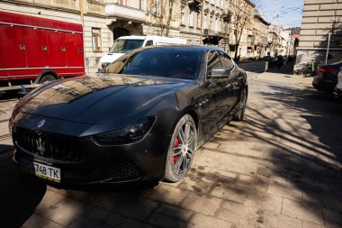 Lviv, Ukrayna - Nisan 06, 2025: Lüks bir Maserati Ghibli arabası güneşli bir günde şehir caddesinde park halinde duruyor