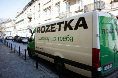 Lviv, Ukrayna - Nisan 06, 2025: Beyaz ve yeşil teslimat van Rozetka Lviv, Ukrayna 'daki eski binaların önüne park etti 