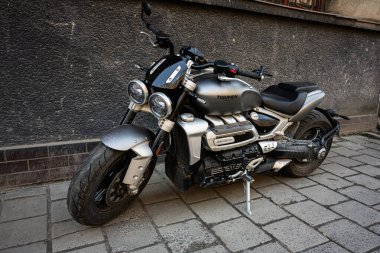 Lviv, Ukrayna - Nisan 06, 2025: Parlak metalik bir Triumph Rocket III motosikleti bir binanın yakınındaki dokulu bir caddede duruyor..