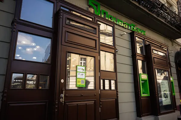 Lviv, Ukrayna - Nisan 06, 2025: Ahşap kapılar ve kentsel mimarinin yansımaları ile klasik Privatbank bankası girişi. 