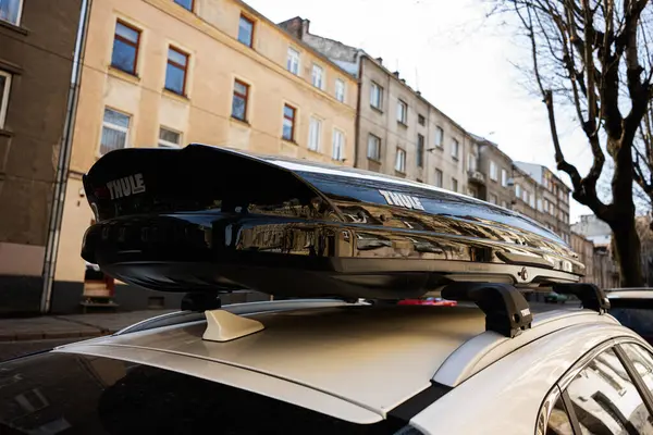 Lviv, Ukrayna - Nisan 06, 2025: Thule çatı kargo kutusu eski şehir binalarının yakınındaki beyaz bir arabaya monte edildi.