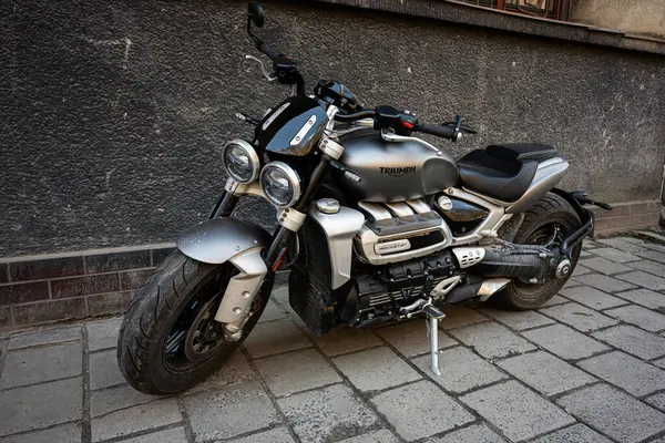 Lviv, Ukrayna - Nisan 06, 2025: Parlak metalik bir Triumph Rocket III motosikleti bir binanın yakınındaki dokulu bir caddede duruyor..