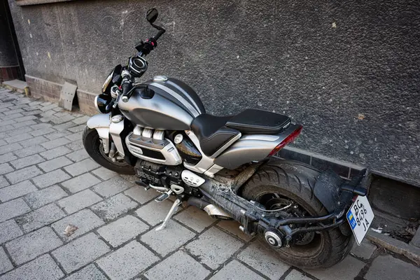 Lviv, Ukrayna - Nisan 06, 2025: Pürüzsüz bir Triumph Roket III motorsikleti engebeli bir beton duvarın kenarına yerleştirilmiş.