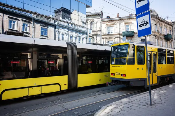 Lviv, Ukrayna - Nisan 06, 2025: Lviv, Ukrayna 'da tarihi ve modern şehir özelliklerine sahip kentsel sokaktan geçen modern sarı tramvay.