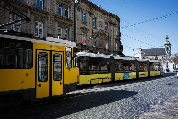 Lviv, Ukrayna - Nisan 06, 2025: Ukrayna 'nın Lviv kentinde antik mimarinin yakınlarındaki tarihi kaldırım taşı caddeleri boyunca canlı sarı bir tramvay turu.