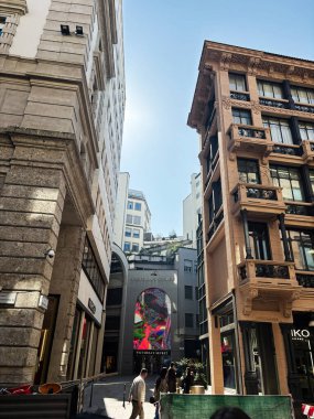 Milan, İtalya - 26 Mart 2025: Milano 'da klasik yapılar ve modern Victoria' s Secret görsellerinin yer aldığı büyüleyici mimari sokak manzarası.
