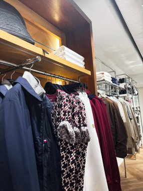 Milan, İtalya - 26 Mart 2025: Tommy Hilfiger modern perakende mağazasında şık bir şekilde düzenlenmiş kıyafetler, moda ve giyim tarzını ön plana çıkarıyor.