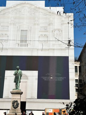 Milan, İtalya - 26 Mart 2025: Milano, İtalya 'da güneşli bir günde koruma altındaki bir cepheden önce Alessandro Manzoni için anıt.