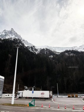 Cenevre, İsviçre - 27 Mart 2025: Dağlık park yerine park etmiş kamyonlar, İsviçre parçalı bulutlu gökyüzü altında.