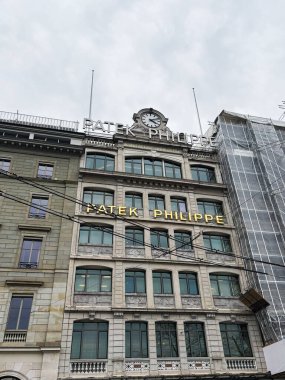 Cenevre, İsviçre - 27 Mart 2025: Cenevre 'de bulutlu bir günde Patek Philippe' in markalaşmasının yer aldığı zarif yapı cephesi.