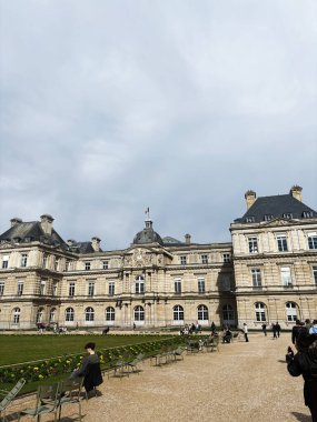 Paris, Fransa - 28 Mart 2025: Paris 'te yemyeşil bahçeler, turistler ve güneşli ortam içeren büyük tarihi yapı