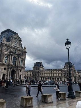 Paris, Fransa - 28 Mart 2025: Paris 'te şehir manzarası, bulutlu gökyüzünün altında ikonik tarihi mimari Louvre.