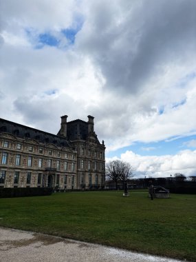 Paris, Fransa - 28 Mart 2025 Paris 'te yeşil çimenli ve parçalı bulutlu gökyüzü olan bir saray.